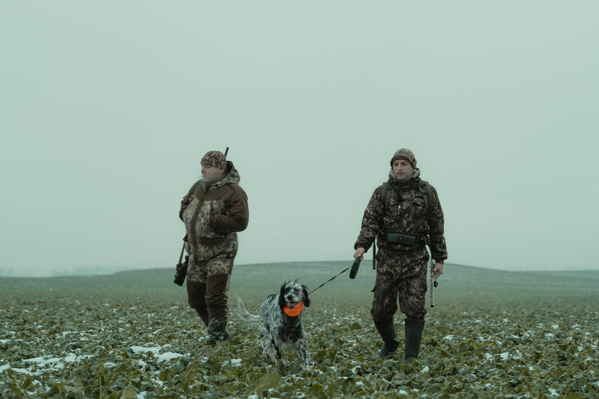 Deux chasseurs et leur chien en plaine